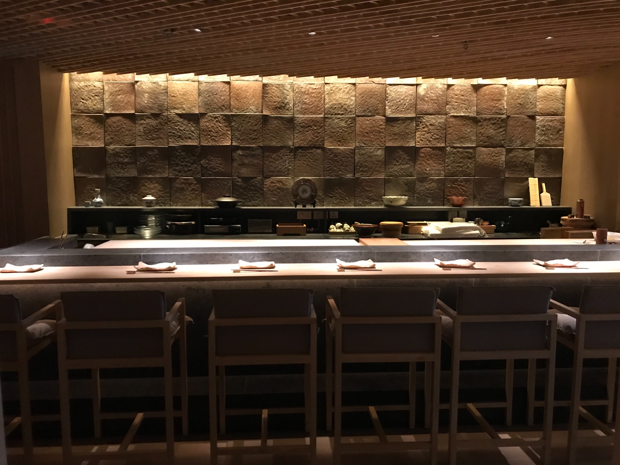 这是一个完全和外面隔开的寿司台,暗红色石墙和黄色灯光为主色调,浑然